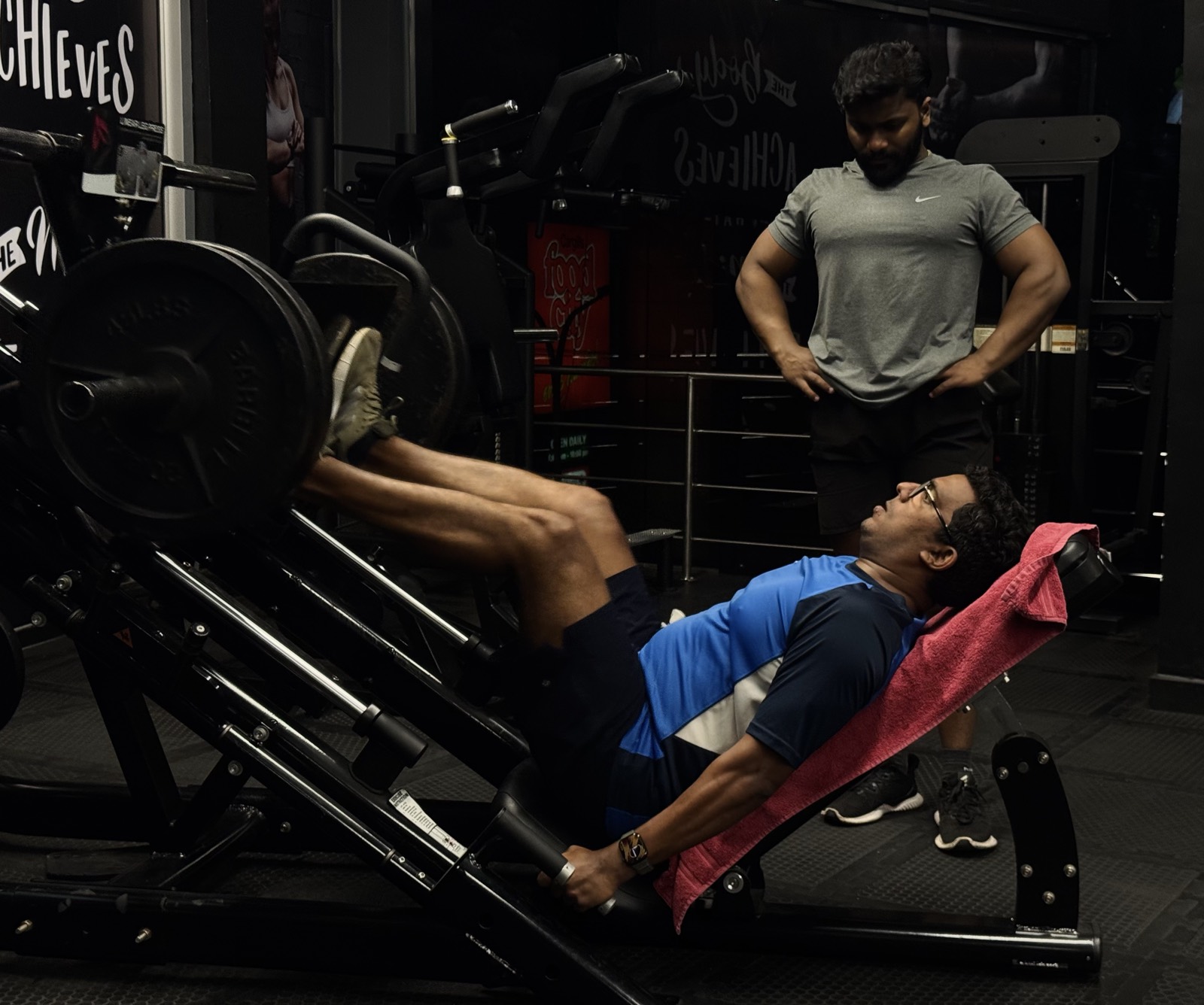 A trainer supervising a member on the leg press at Premium Fitness